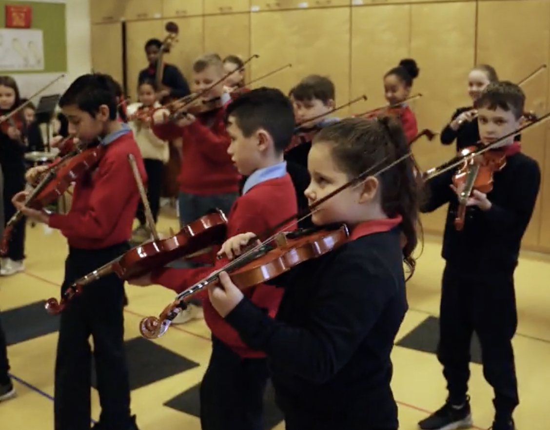 Children playing violins together in the PRESTO music programme